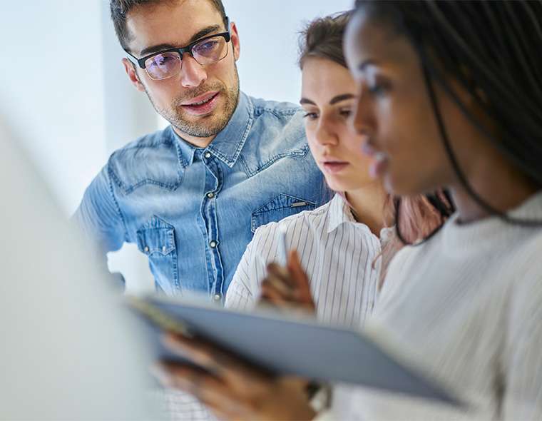 Three employees discussing with their notes in hand