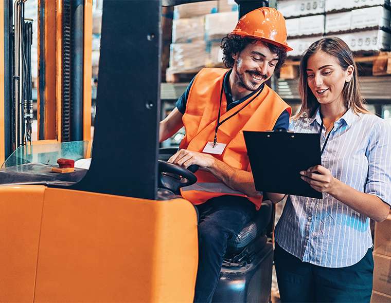 Worker on forklift talking to a team member with a clipboard